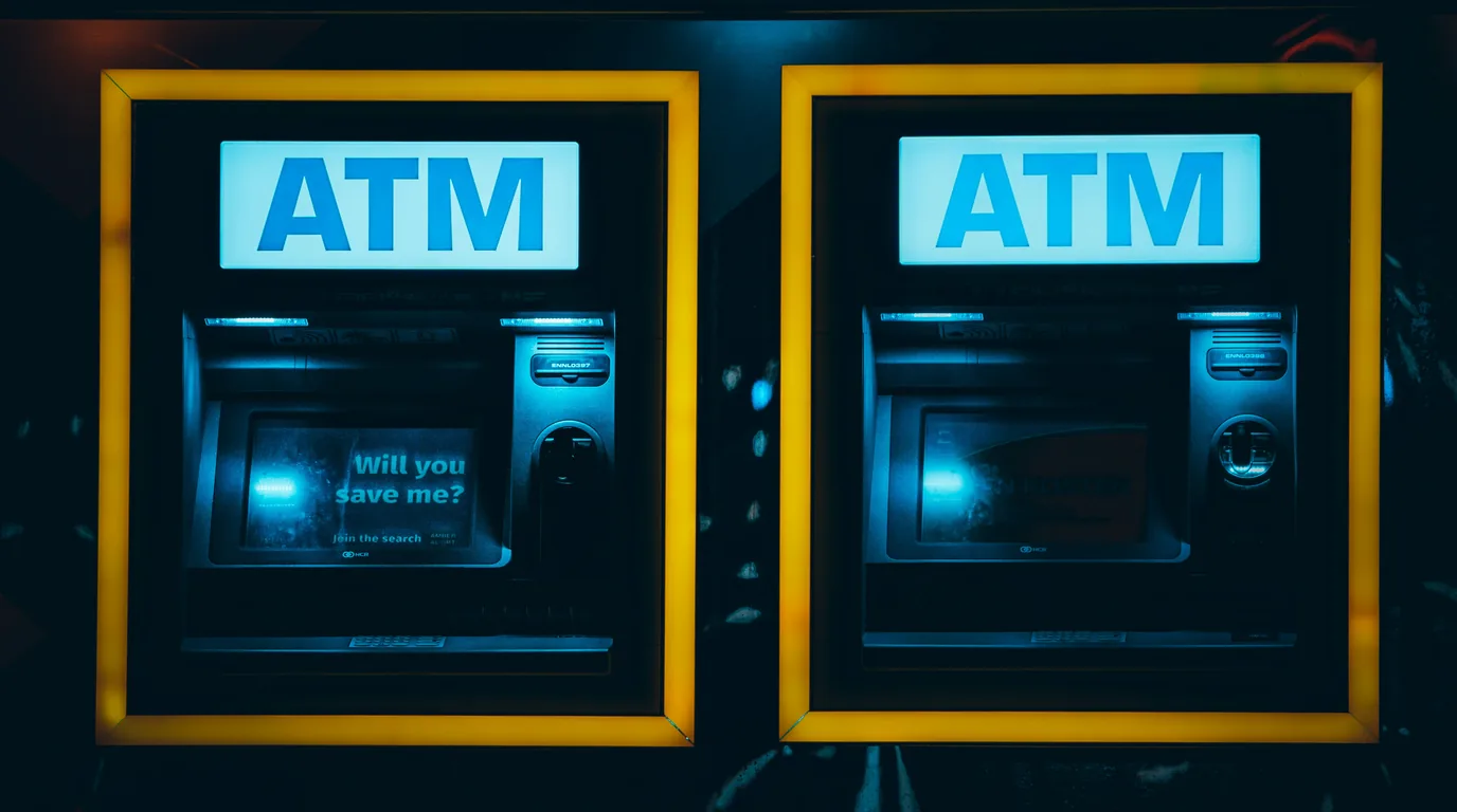 Two cash machines glowing blue inside bright yellow surrounds.