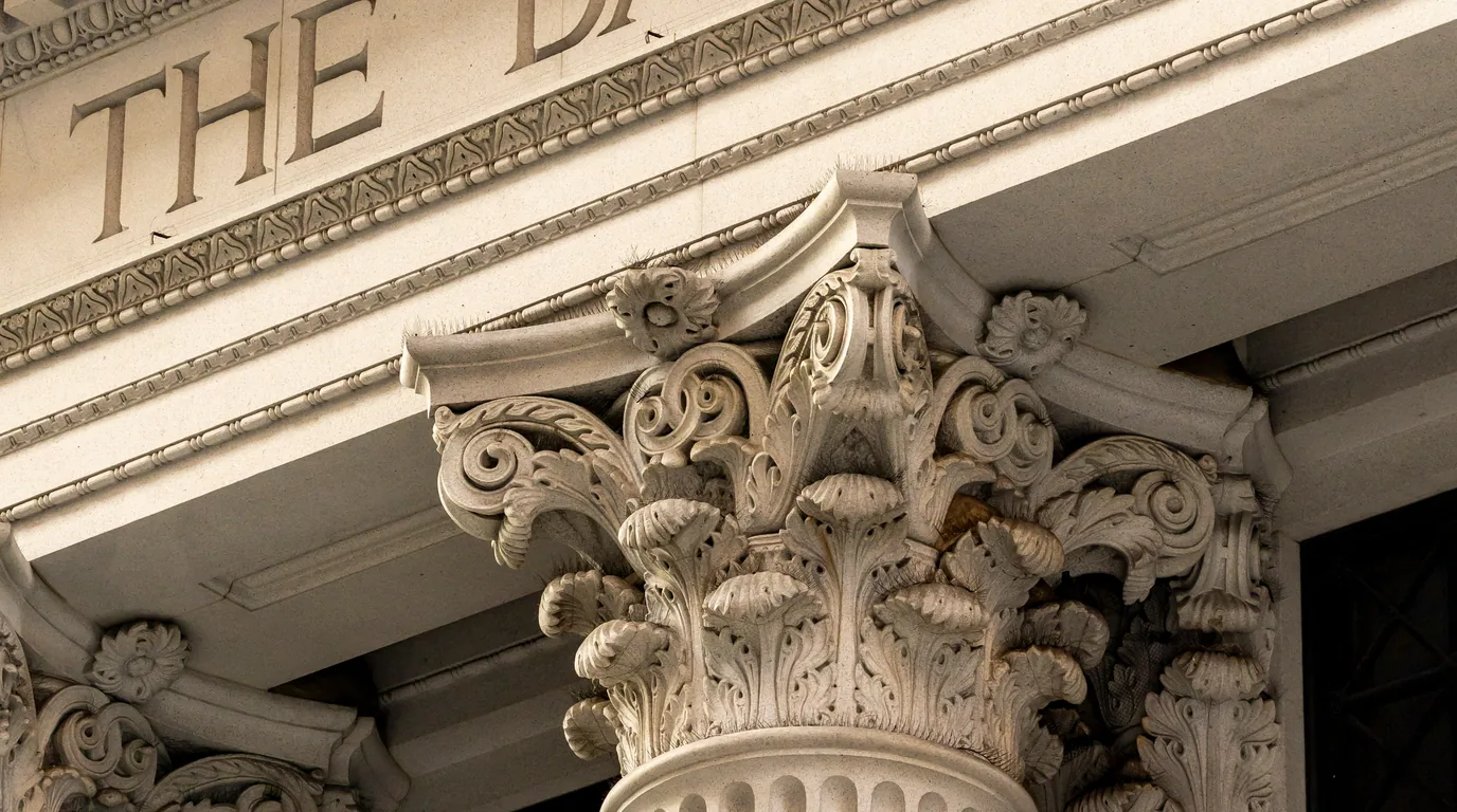 A carved Corinthian capital, acanthus leaves and volutes in pale stone.