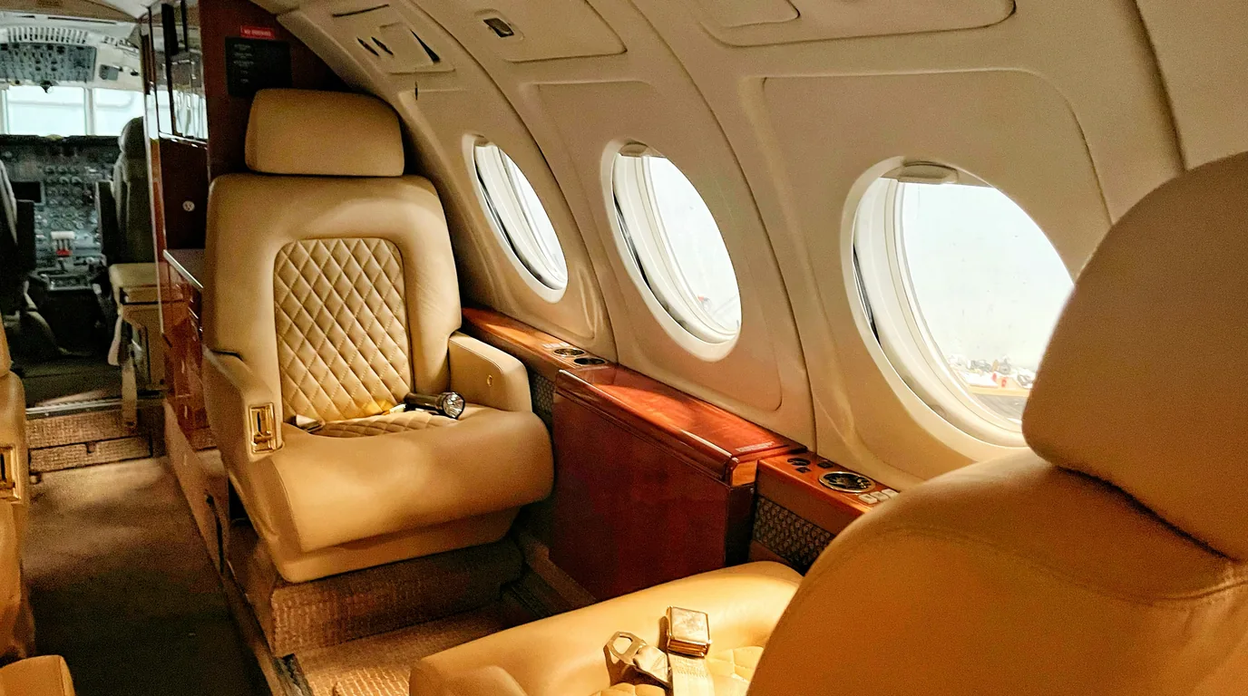 Cream quilted leather seats and oval windows in the cabin of a private jet.