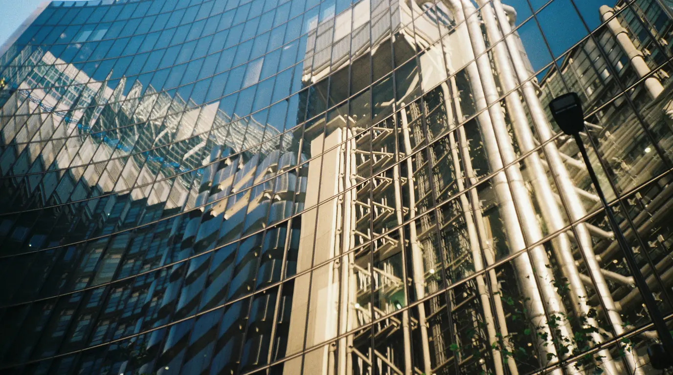 A curved wall of glass and exposed steel ducting on an office tower, seen from below.