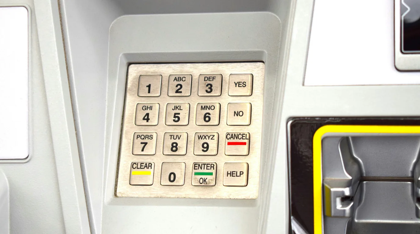 Worn brushed-metal cash machine keys, MNO and WXYZ legible on the caps.