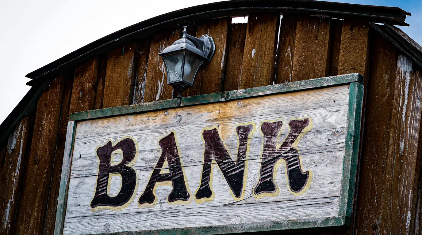 A painted wooden sign reading BANK on a shingled gable.