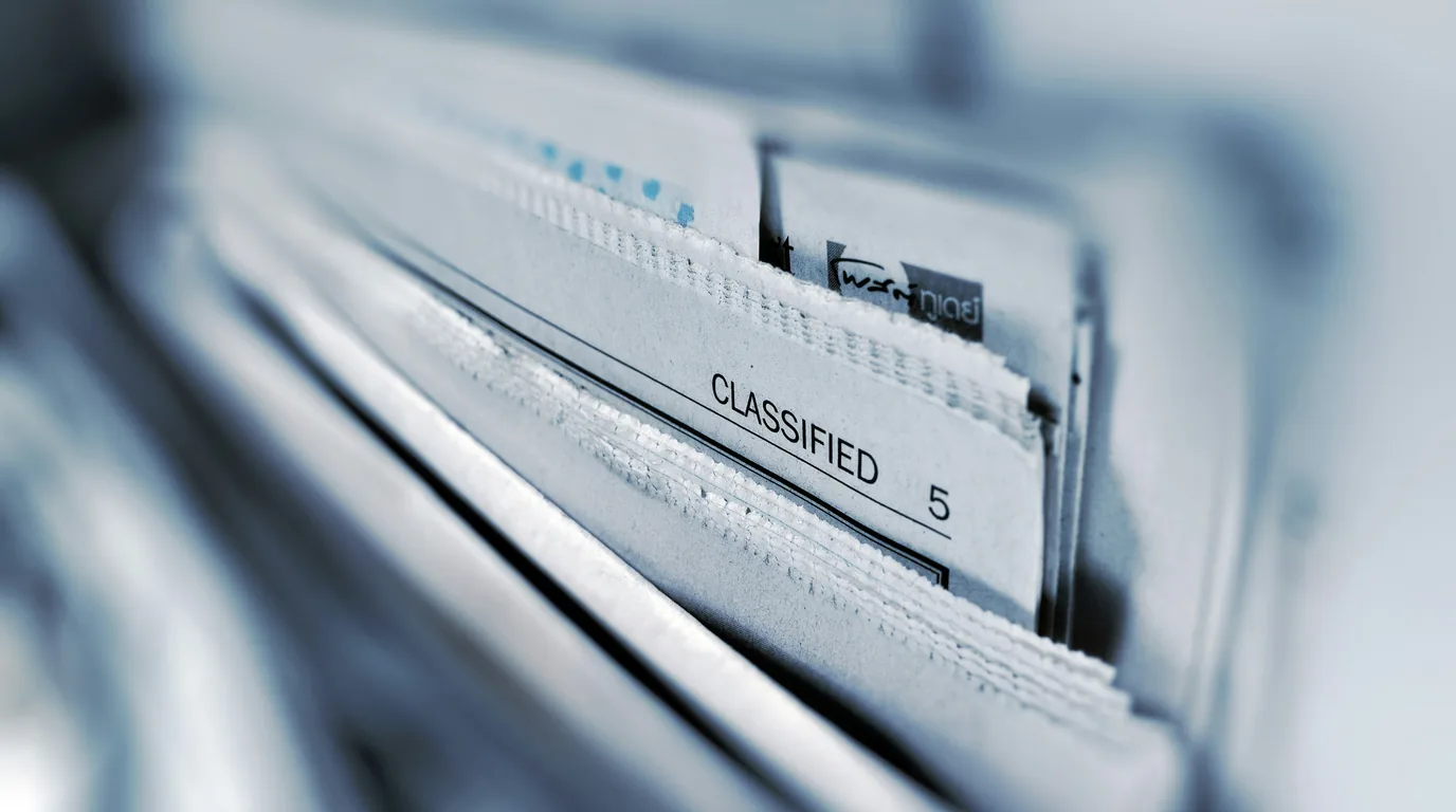 A row of file dividers, the tab nearest the lens reading CLASSIFIED.