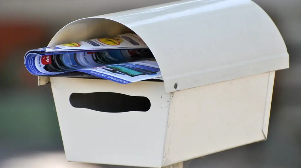 A white mailbox stuffed with letters and leaflets