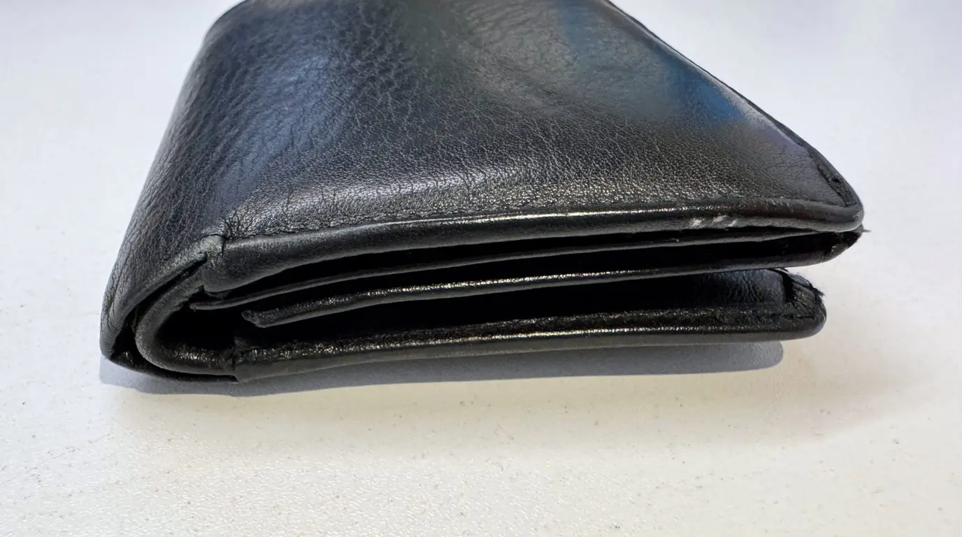 A folded black leather wallet on a pale surface